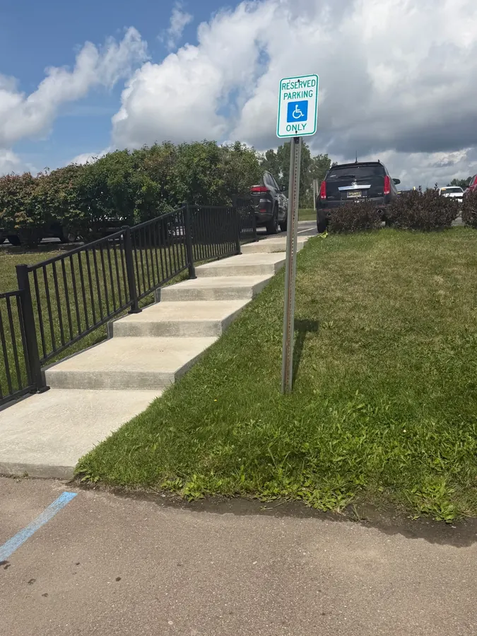 Concrete steps and walkway with black safety railing at a commercial property