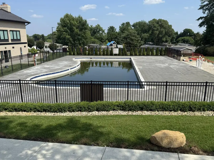 Completed light-colored concrete deck surrounding a residential pool