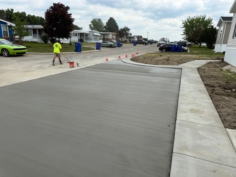 Concrete finisher working across a newly placed driveway