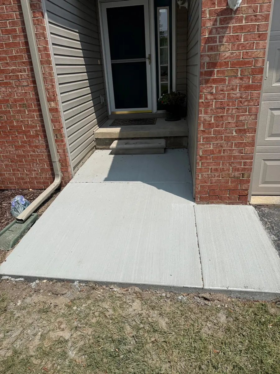 New concrete walkway and entry landing between brick walls