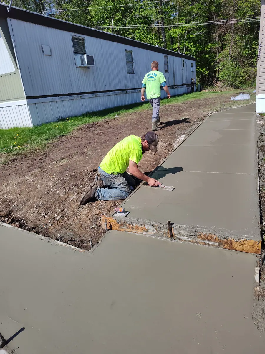 Concrete finisher troweling a newly placed residential sidewalk