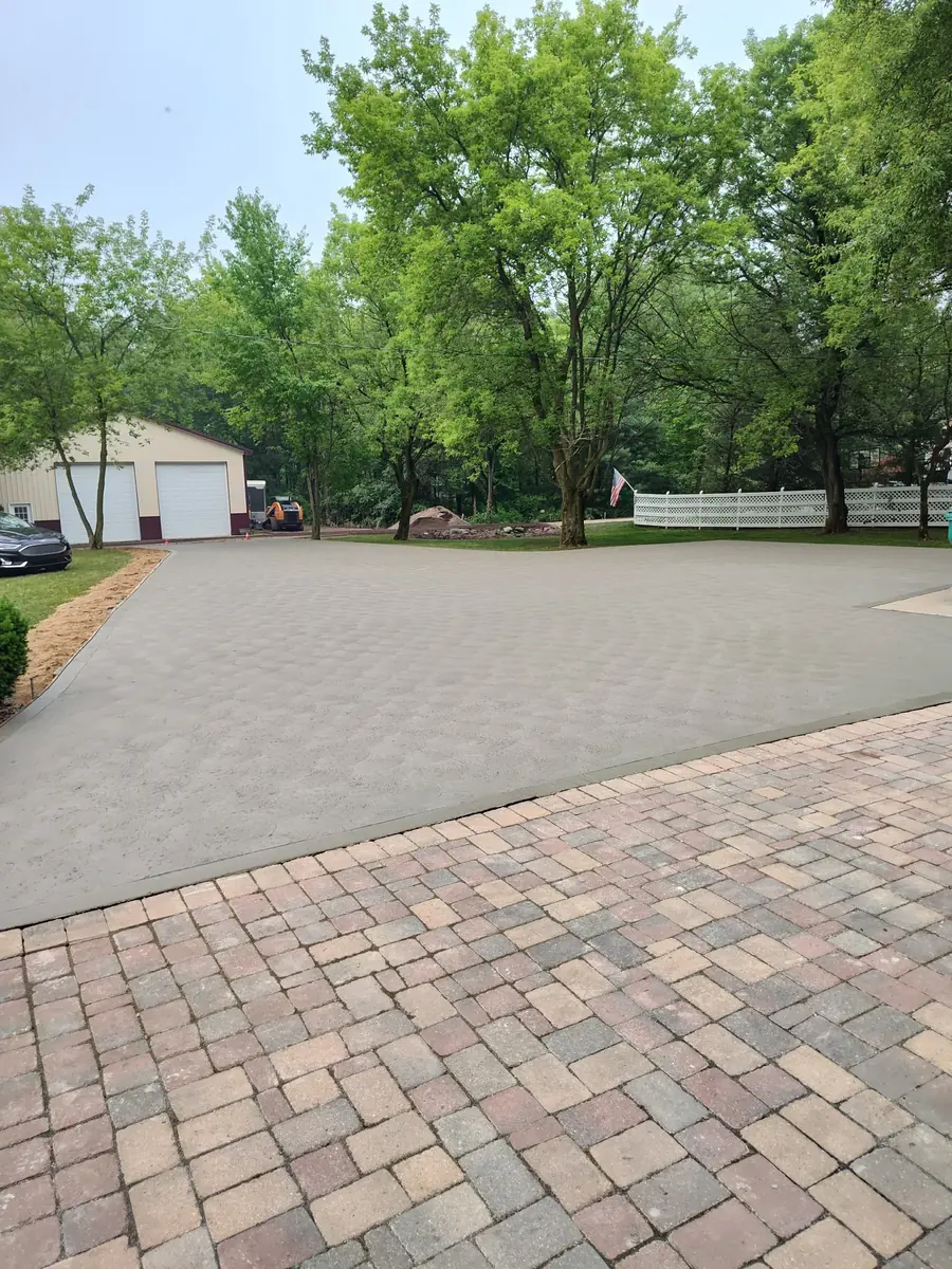 Finished concrete driveway meeting an existing paver apron