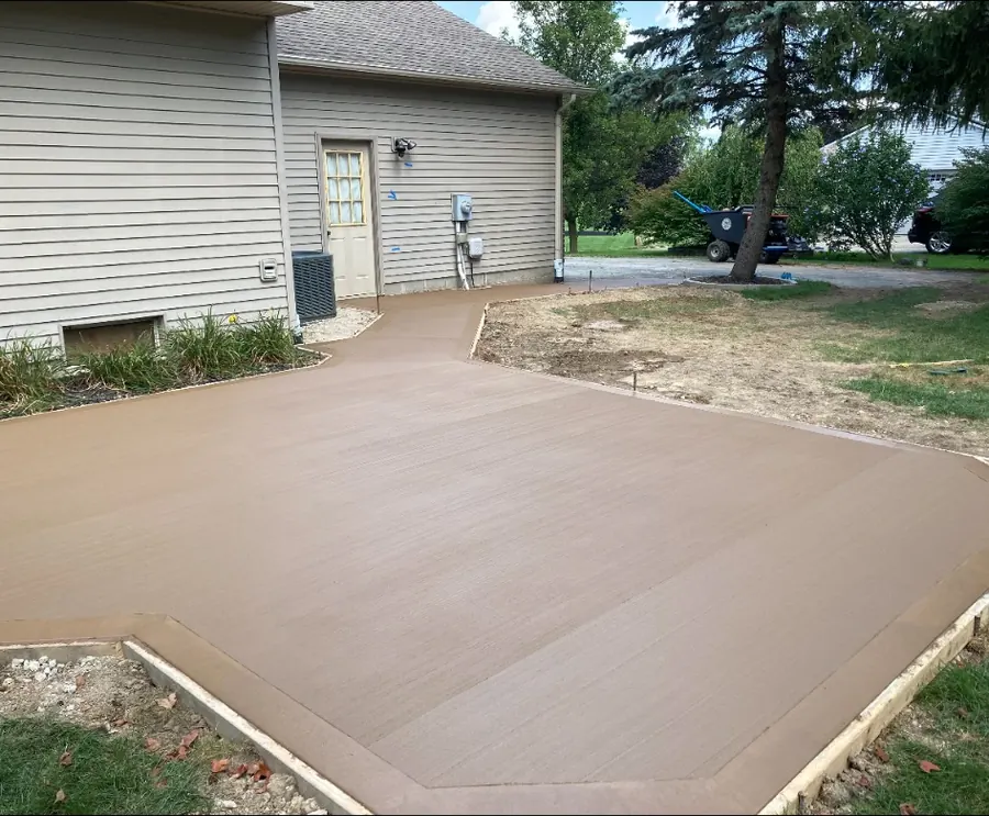 Freshly finished concrete patio and walkway beside a home