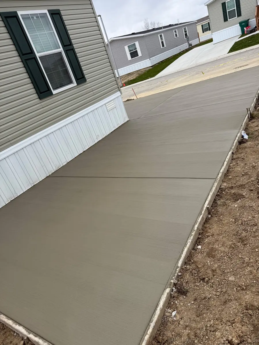 Long new concrete driveway installed beside a home
