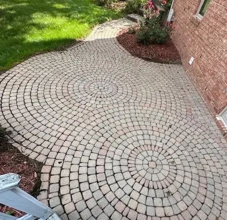 Circular-pattern paver walkway beside a brick home