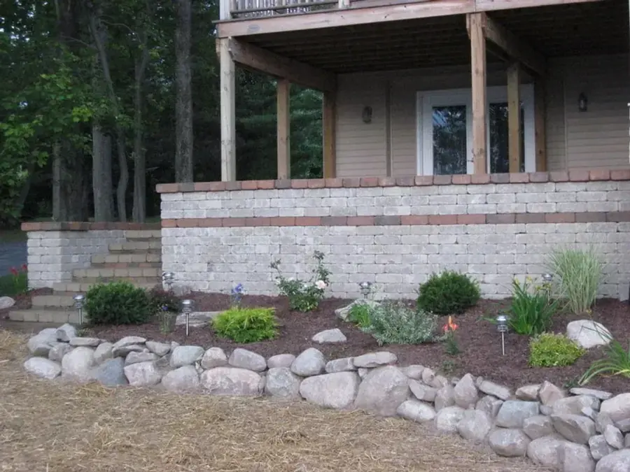 Stone retaining wall and landscaped bed beside a residential deck