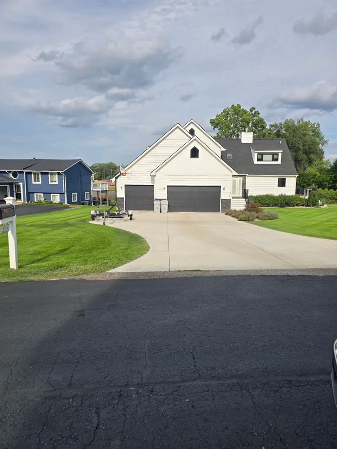 Wide residential concrete driveway leading to a three-car garage